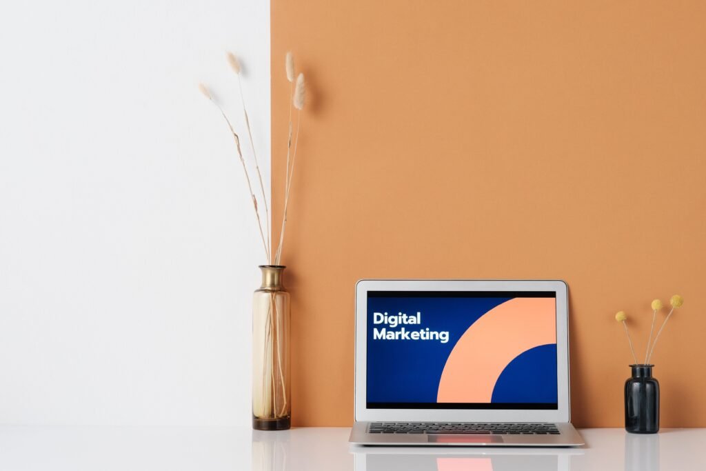 A laptop on a desk with digital marketing graphics, surrounded by stylish vases.